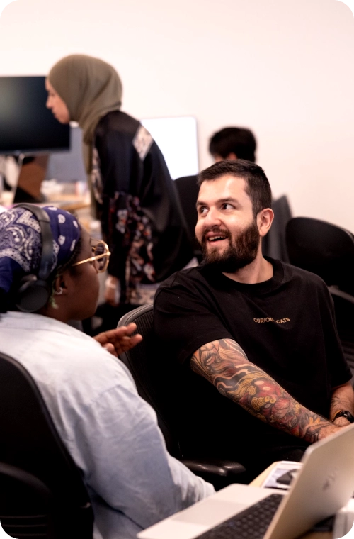 Two Coactive team members seated at a desk, each using a laptop, engaged in a collaborative work session.
