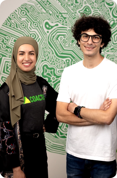 Two individuals stand side by side against a vibrant green backdrop, creating a lively and engaging scene.