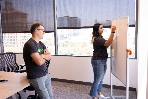 Two Coactive team members collaborating in our San Jose office, discussing ideas in front of a whiteboard filled with notes and diagrams.