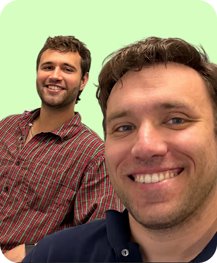 Two smiling men, one in a red checkered shirt and the other in a navy blue shirt, against a light green background.