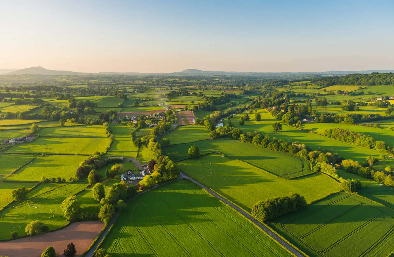 An aerial view of UK countryside showing a patchwork of green fields and trees