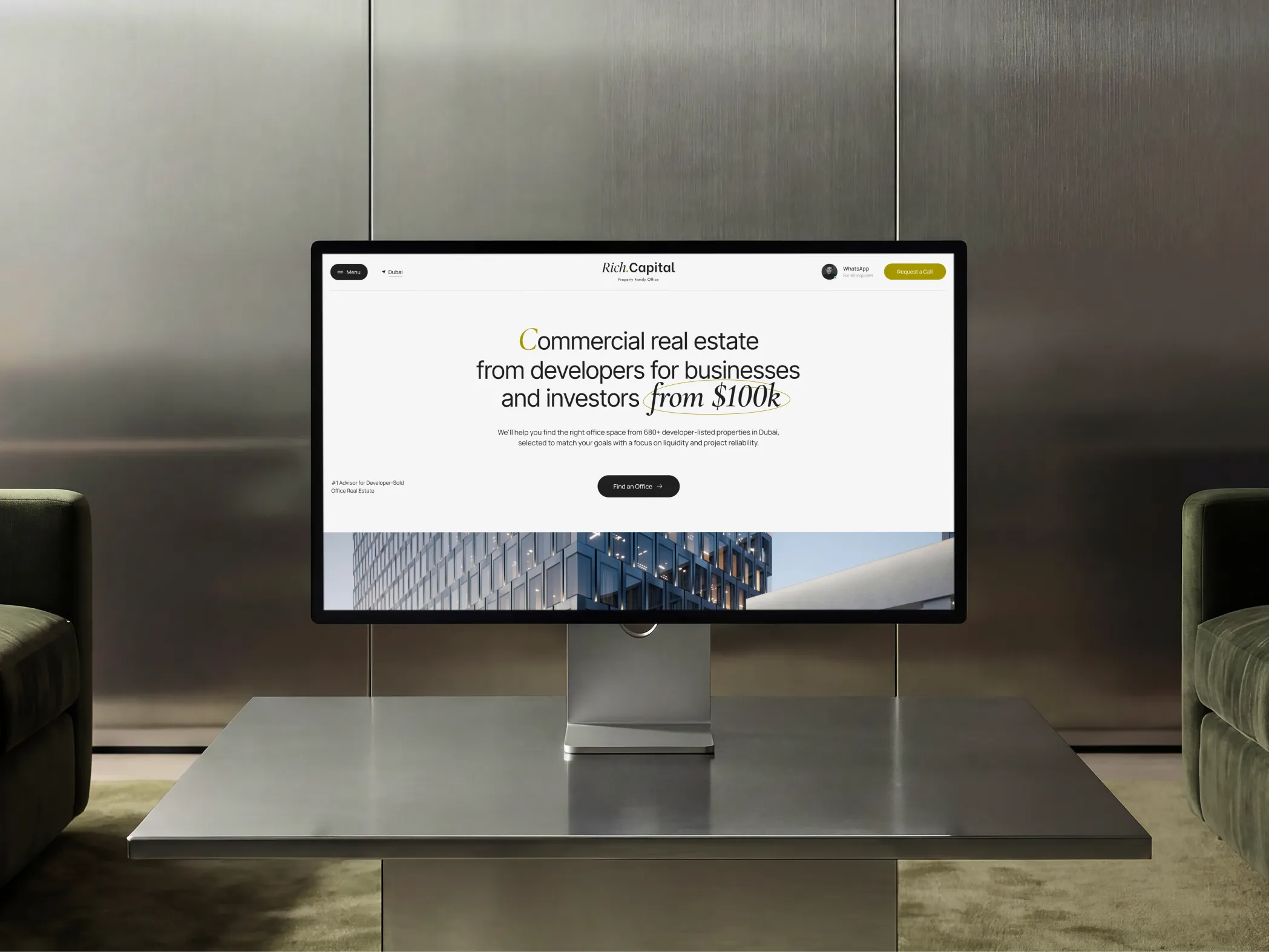 Computer screen on table showing Rich Capital real estate website homepage with office space info.