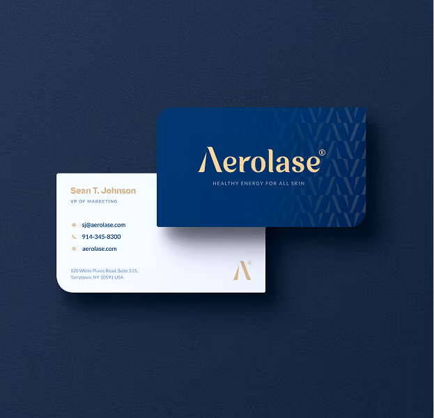 Two business cards for Aerolase on a dark blue background: one card is navy blue with the gold Aerolase logo and the tagline 'Healthy Energy for All Skin,' the other is white displaying contact details for Sean T. Johnson, VP of Marketing, including email, phone number, website, and office address in Tarrytown, NY.