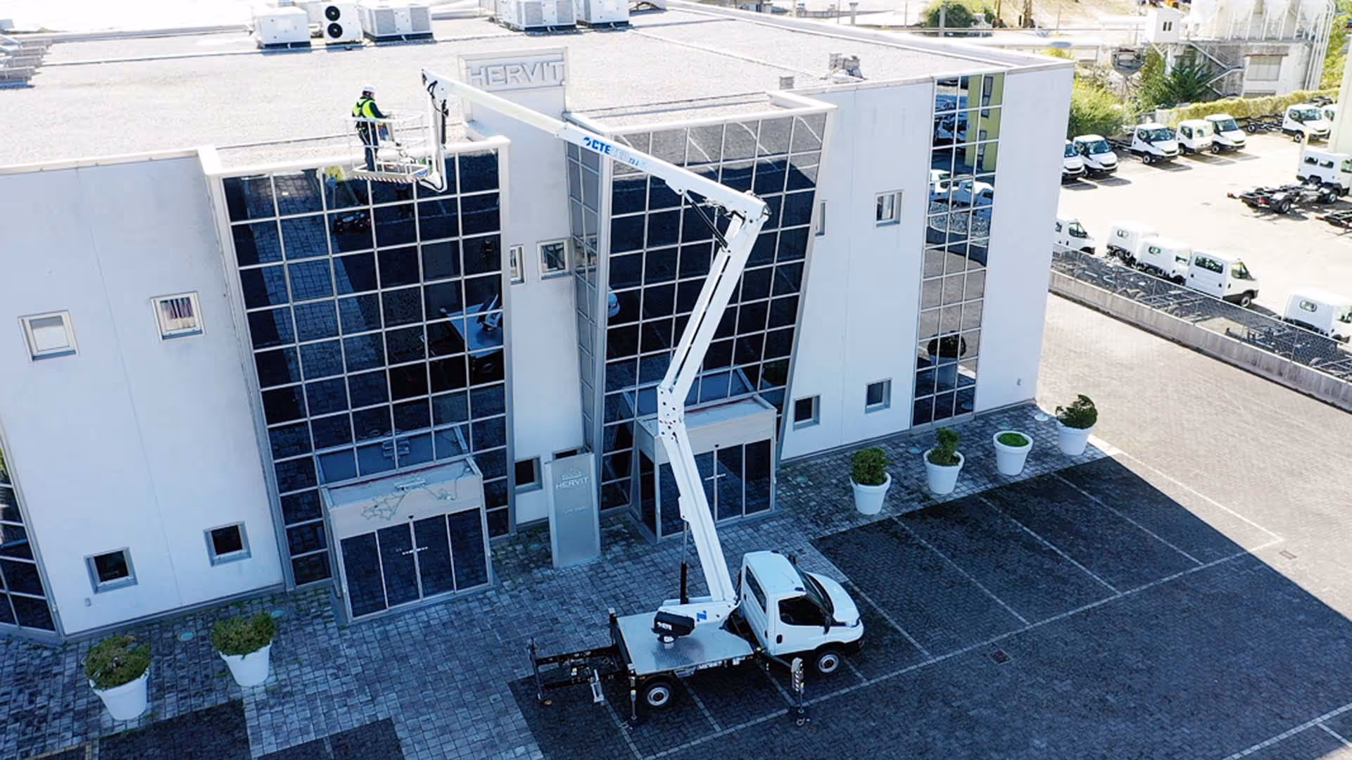 A worker on a raised platform inspects the roof of a commercial building.