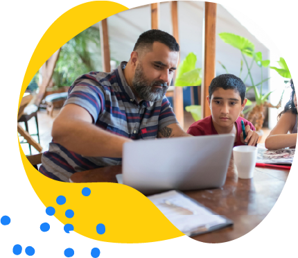 Man and boy sitting at a table working together on a laptop.
