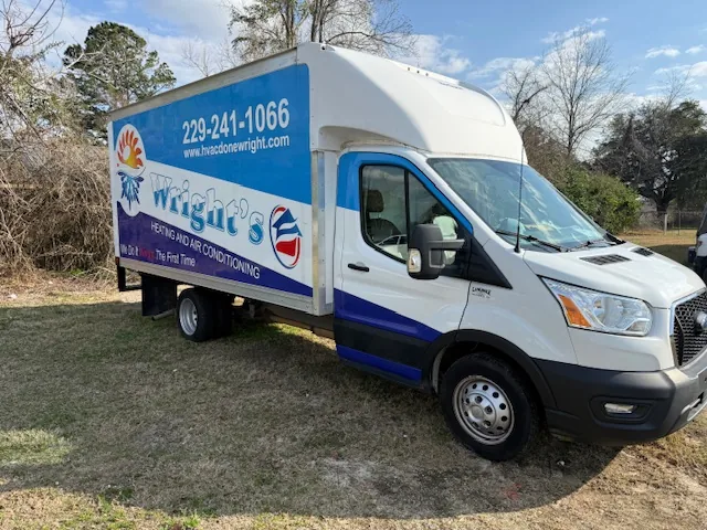 White and blue box truck parked on grass with advertisement for Wright's Heating and Air Conditioning and contact phone number 229-241-1066.