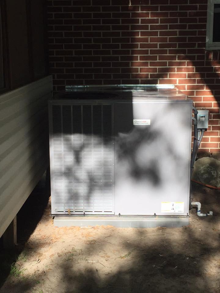 HVAC Contractor in Bemiss GA installing residential air conditioning condenser unit against brick wall
