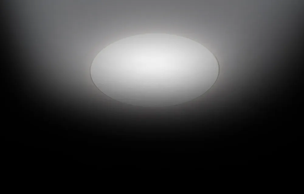 Rundes eingebautes Deckenlicht, das ein weiches, diffuses Licht in einen dunklen Raum abstrahlt.