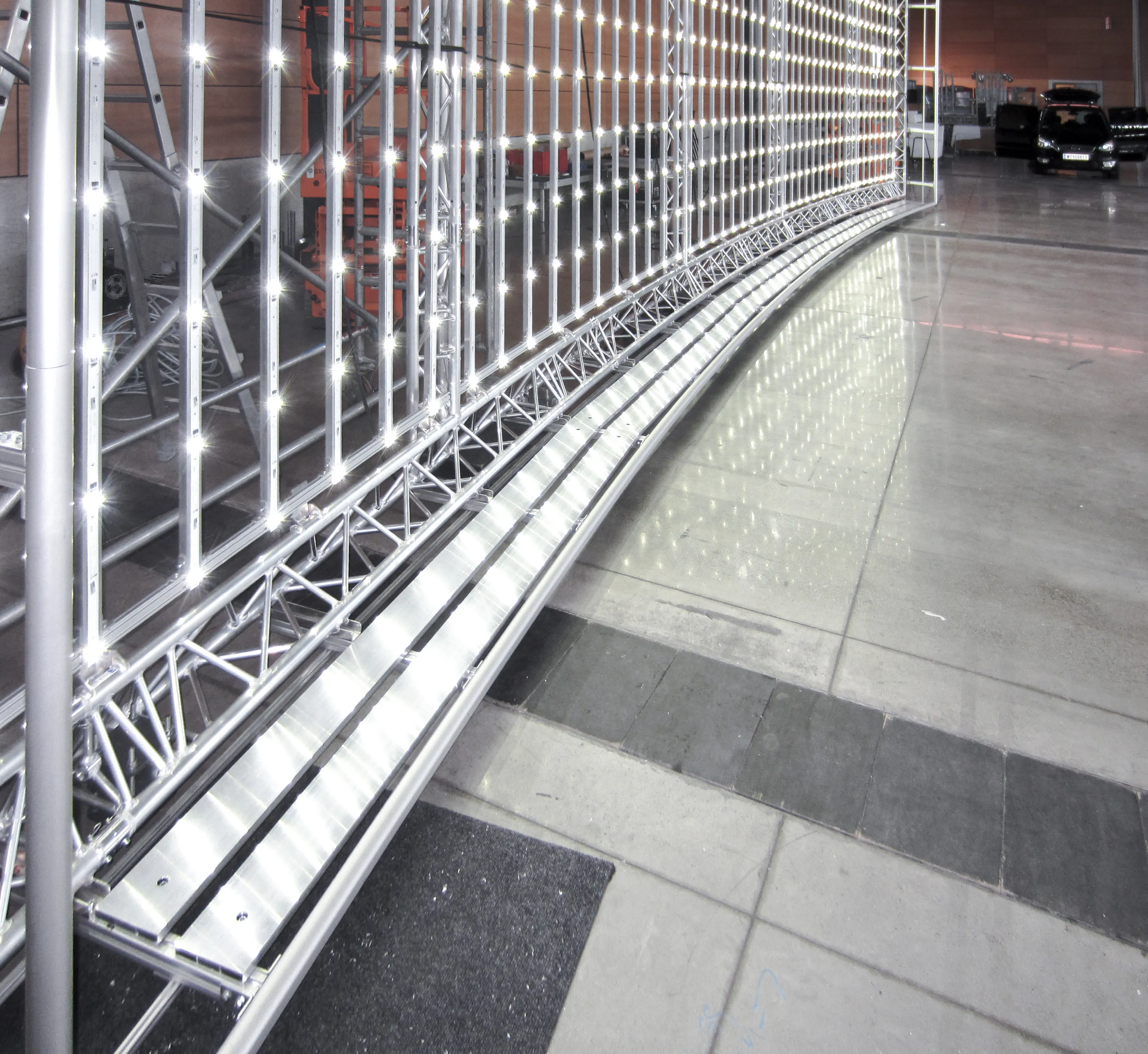 Gebogene LED-Lichtwand mit hellen LEDs auf silbernem Metallgestell in einer Industriehalle.