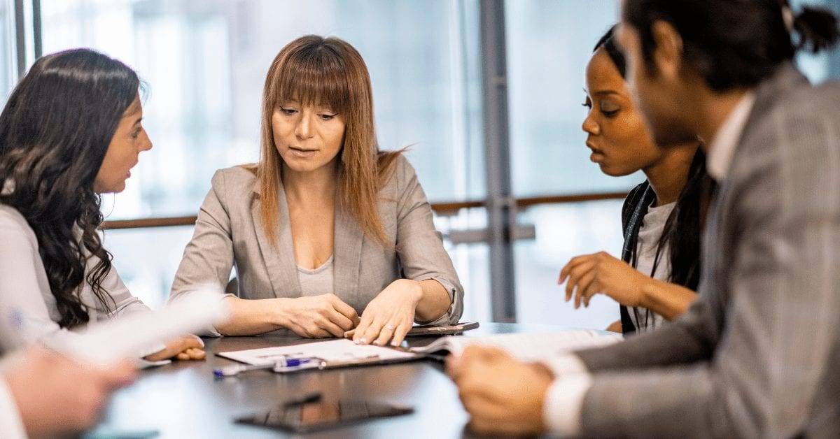 Four professionals reviewing documents and discussing coworking space management agreements at a meeting table.