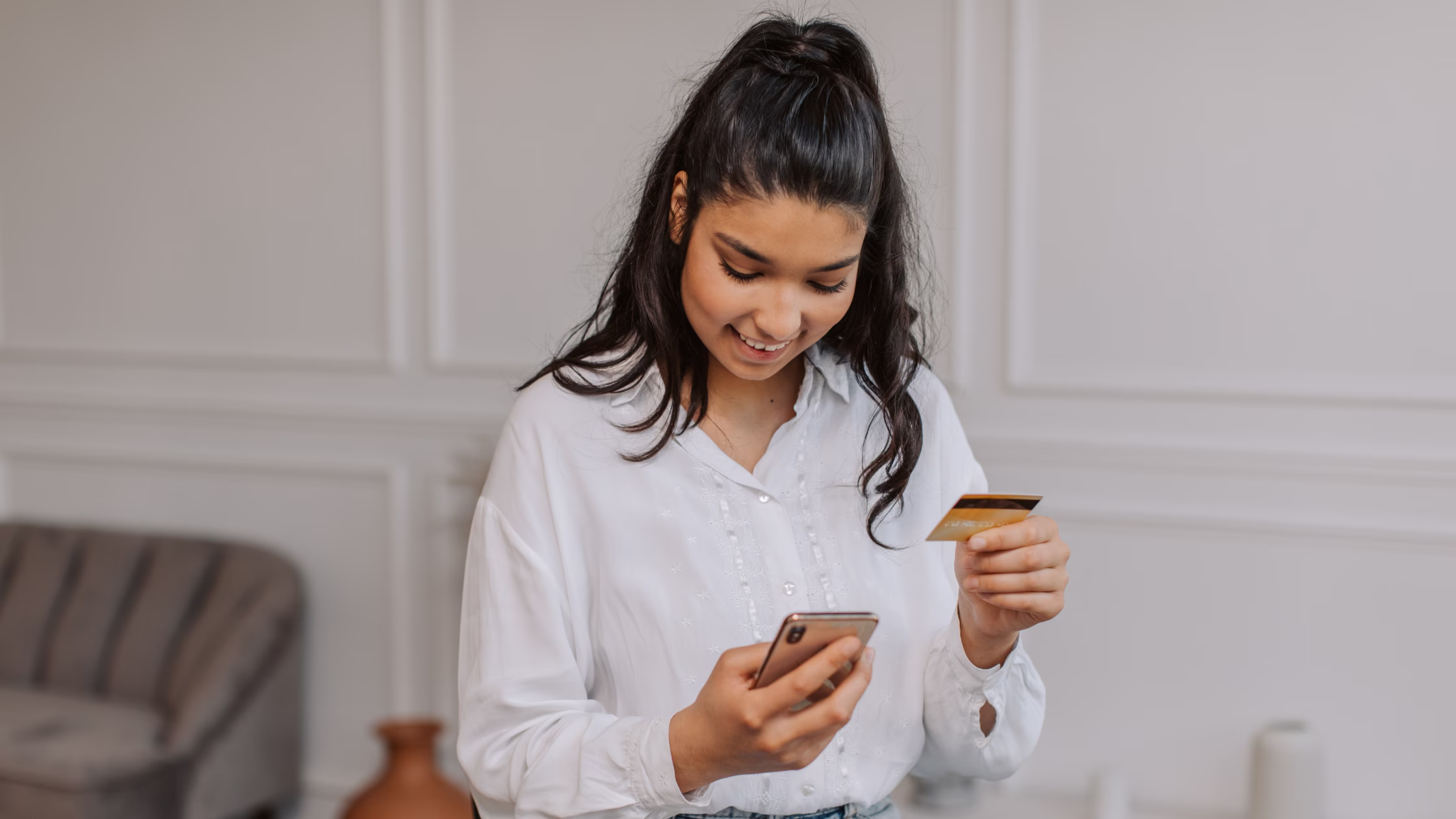 Woman making a secure payment by entering credit card details on her phone in a coworking workspace.