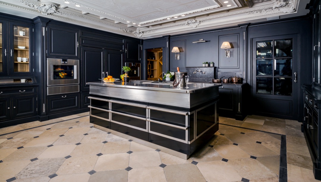 Stilfullt kjøkken med svart skap innredning, stor midtøy i rustfritt stål og marmorgulv.