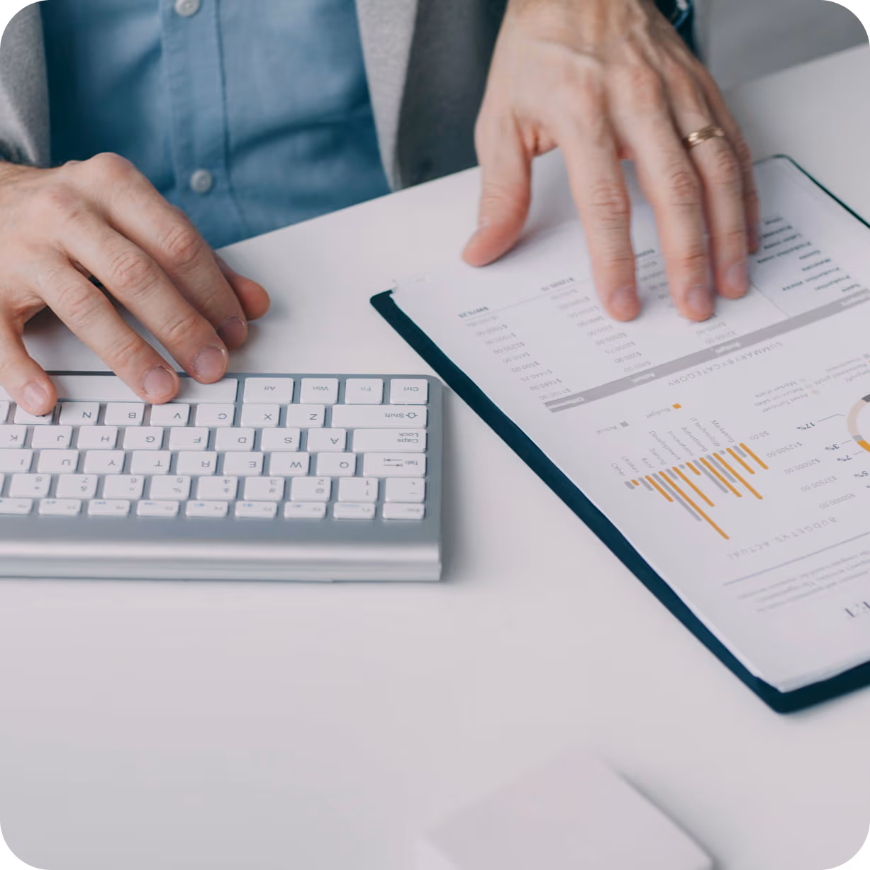 homme qui tape au clavier d'ordinateur avec fiche statistiques posée à côté