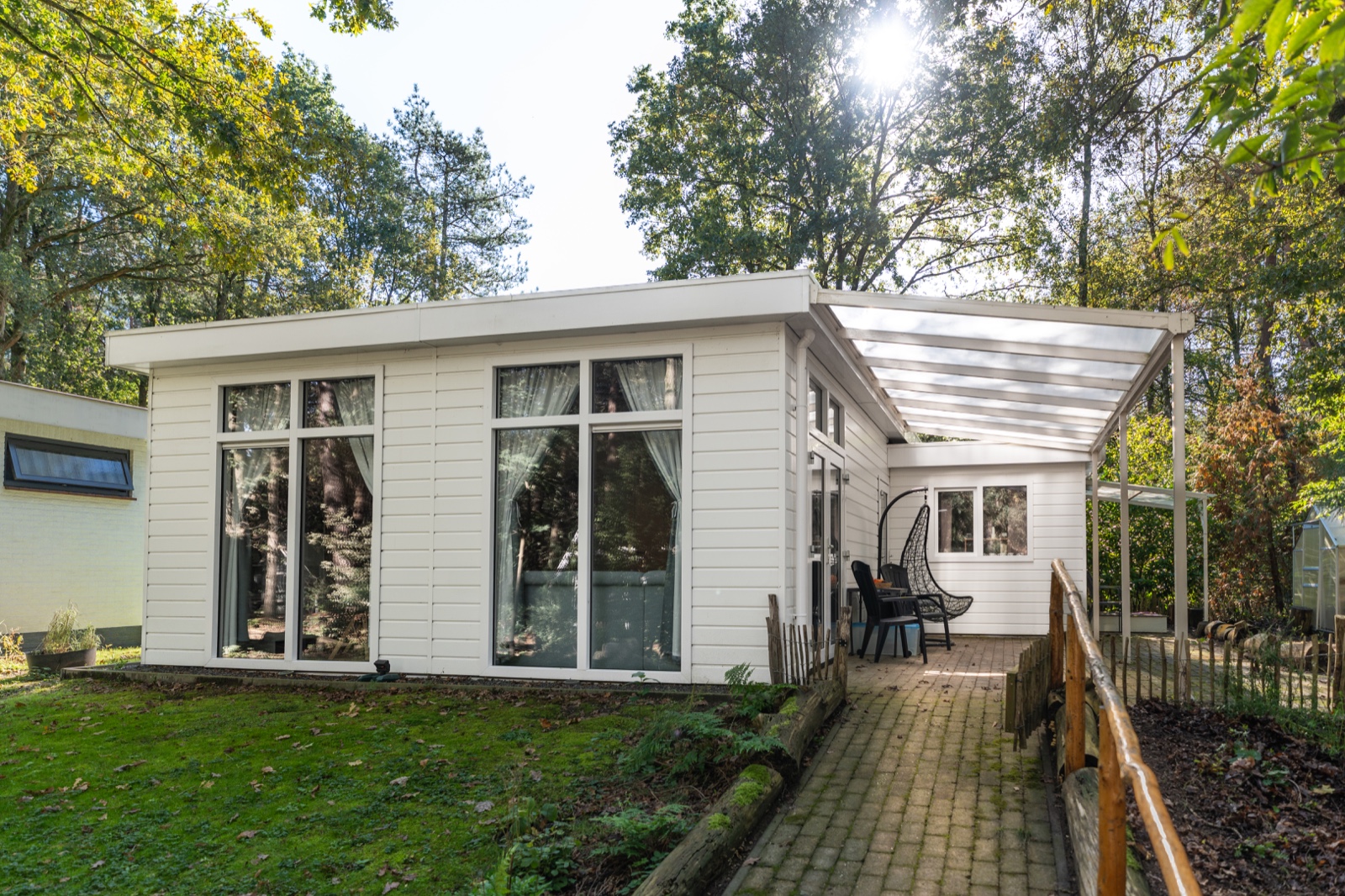 Witte houten mantelzorgwoning in Rucphen met tuindeuren en veranda in een bosrijke tuin