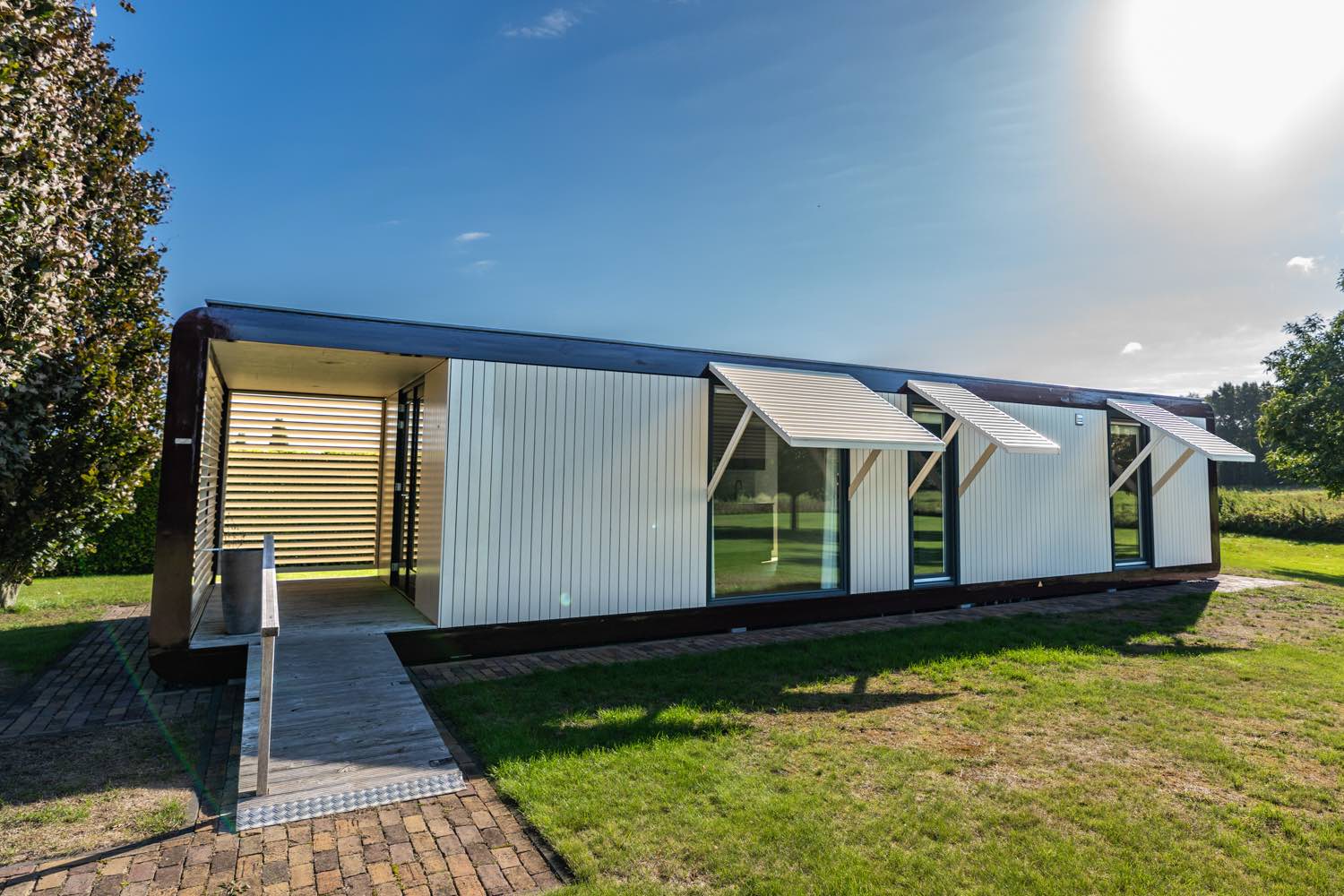 Moderne gelijkvloerse mantelzorgwoning in Reuver met lichte gevel en zonwering op een grasveld