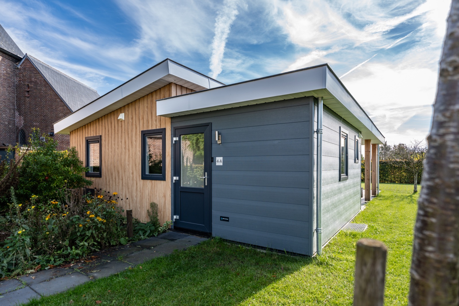 Gelijkvloerse mantelzorgwoning in Heteren met houten en grijze gevel naast een kerk