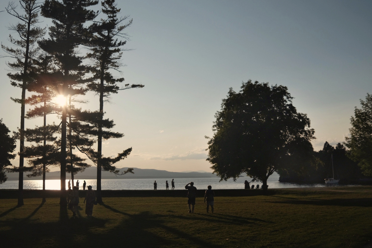 The sun sets over a park and the water of Lake Champlain in Burlington, Vermont.