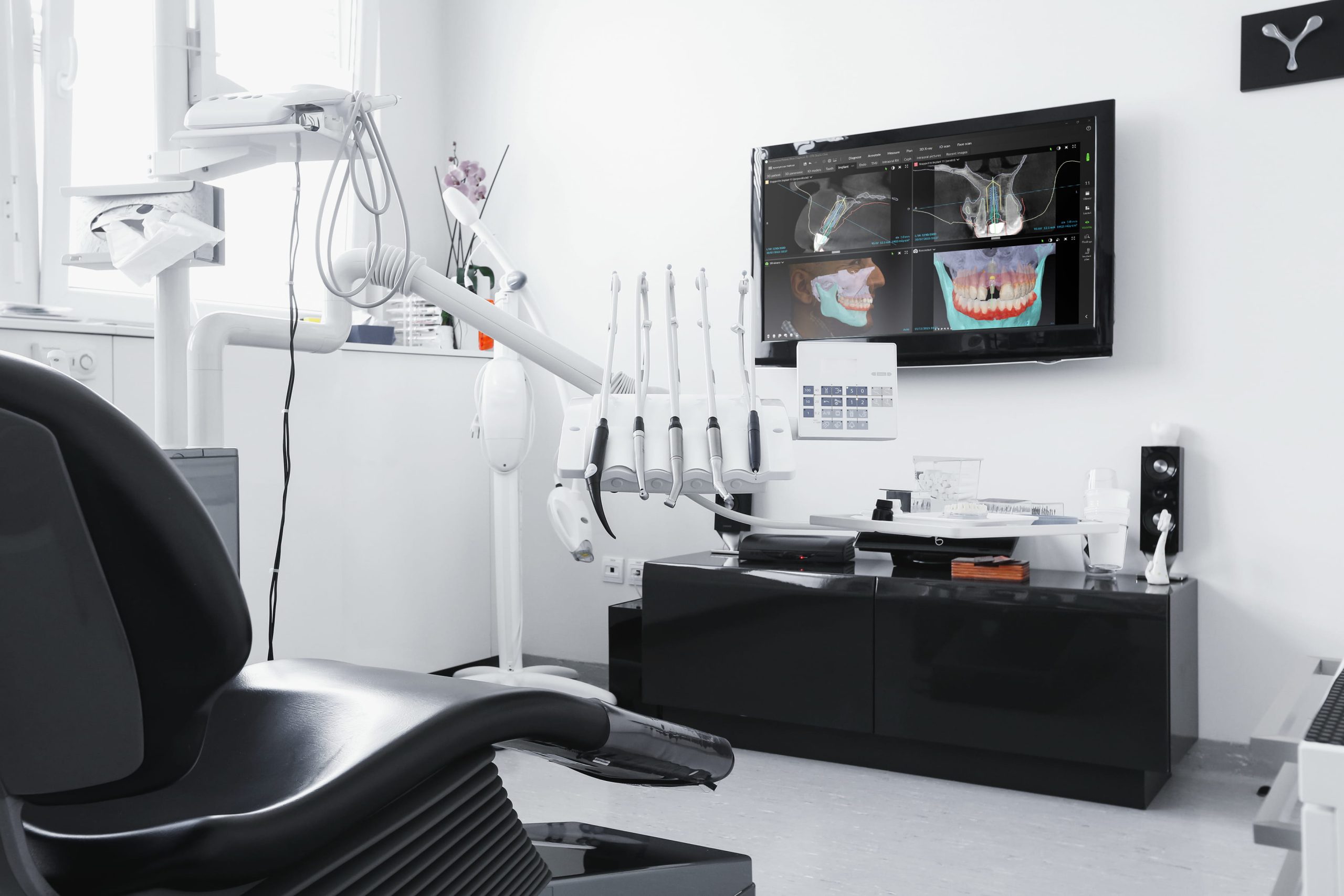 Modern dental office with a dental chair, tools, and screen showing dental X-ray images.