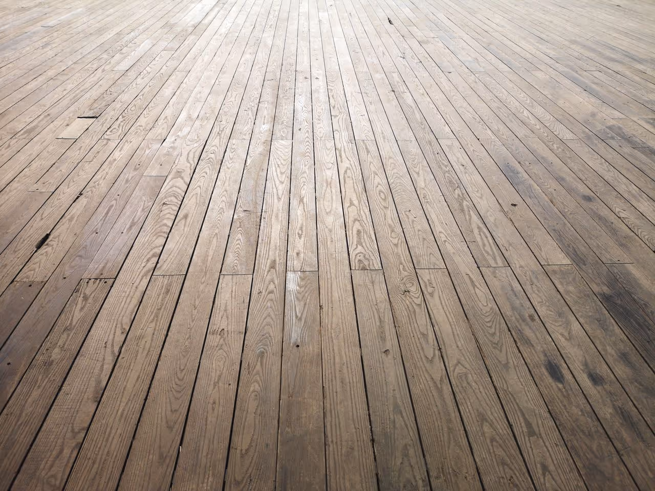Holzboden mit langen Dielen, die sich perspektivisch zum Hintergrund verjüngen.