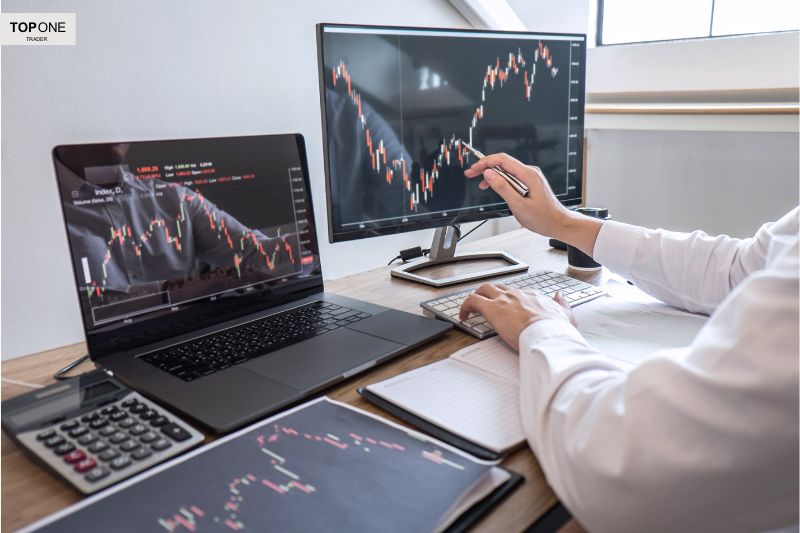Trader analyzing charts on multiple screens to determine the best time frame for day trading and making strategic market moves