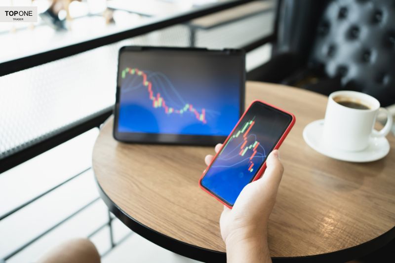 Trader monitoring stock market charts on phone and tablet, learning strategies on how to become a successful trader efficiently.