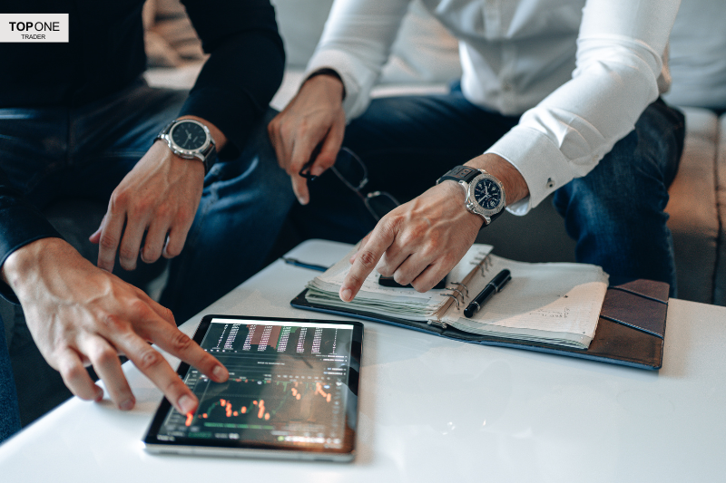 Traders analysing bull flag pattern on tablet for prop firm strategy discussion