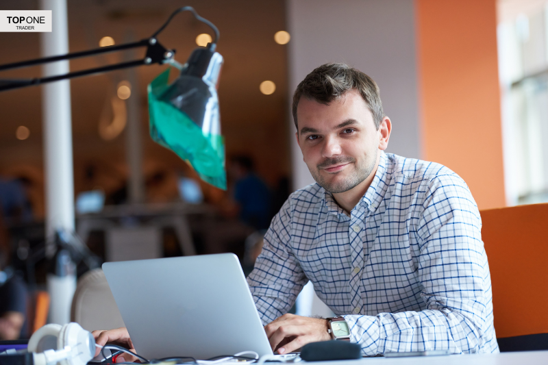 Confident trader at desk with laptop — exploring the question, are prop firms a scam?