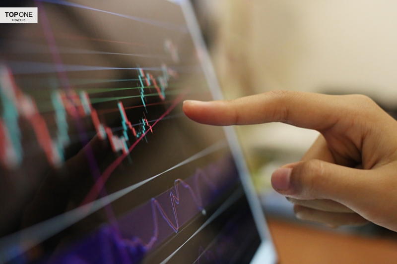 Trader analysing chart patterns on screen, potentially spotting a cup and handle pattern formation.
