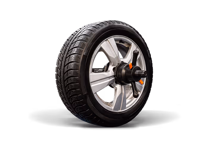 Car wheel with silver alloy rim mounted on a balancing machine against black background.