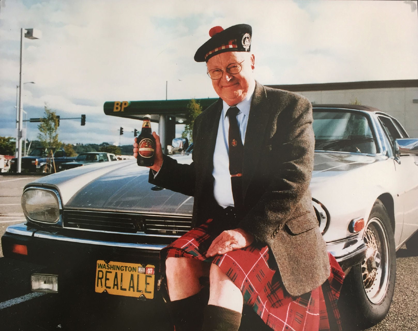 Bert Grant holding a beer beside car with "REALALE" license plate