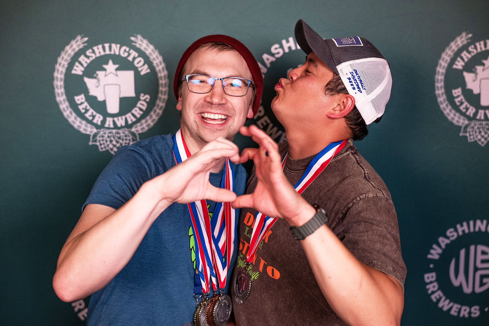 Attendees smiling in front of Washington Beer Awards backdrop at the Craft Beer Summit 2024