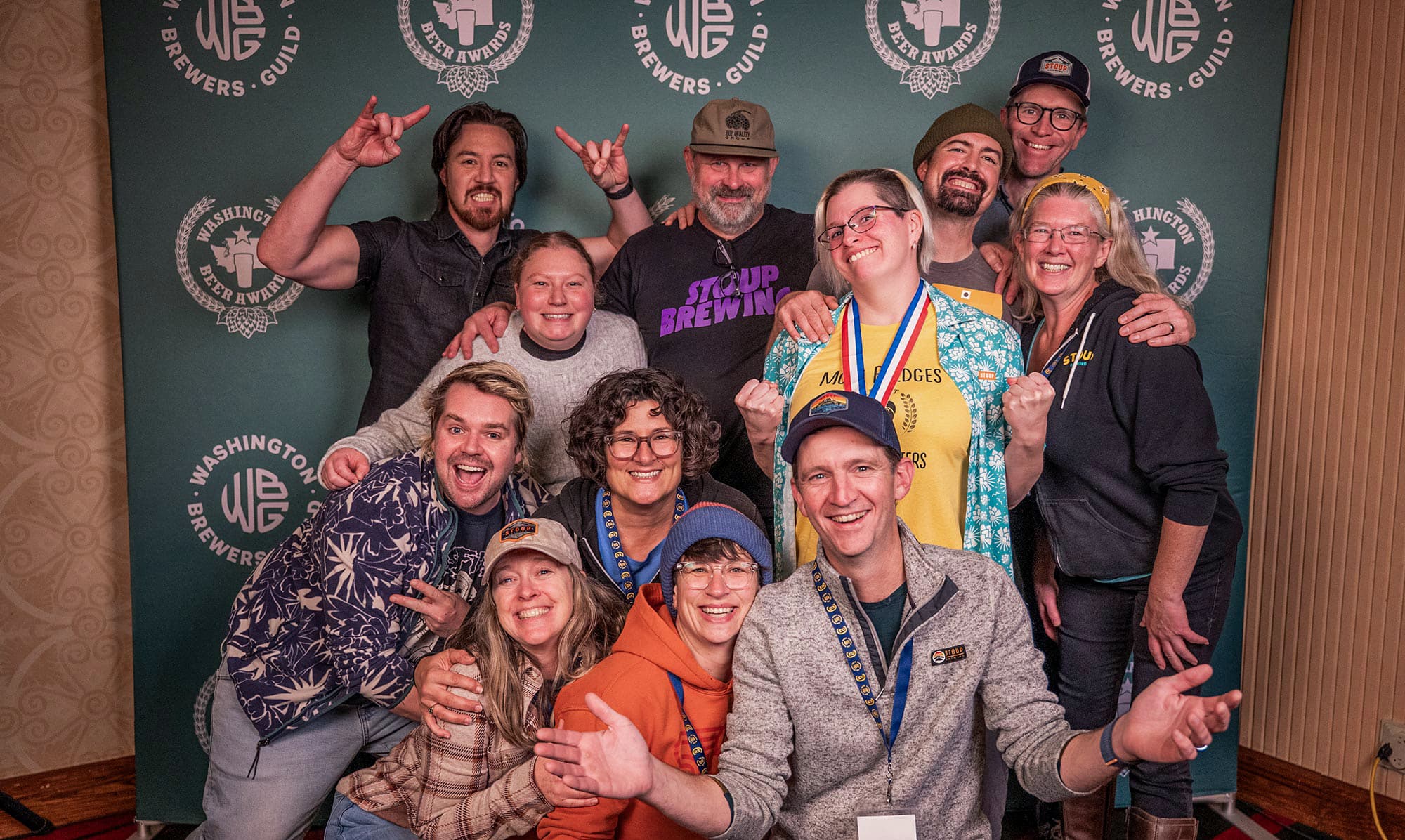 Brewery workers posing in front of Washington Beer Awards backdrop at Craft Beer Summit 2025