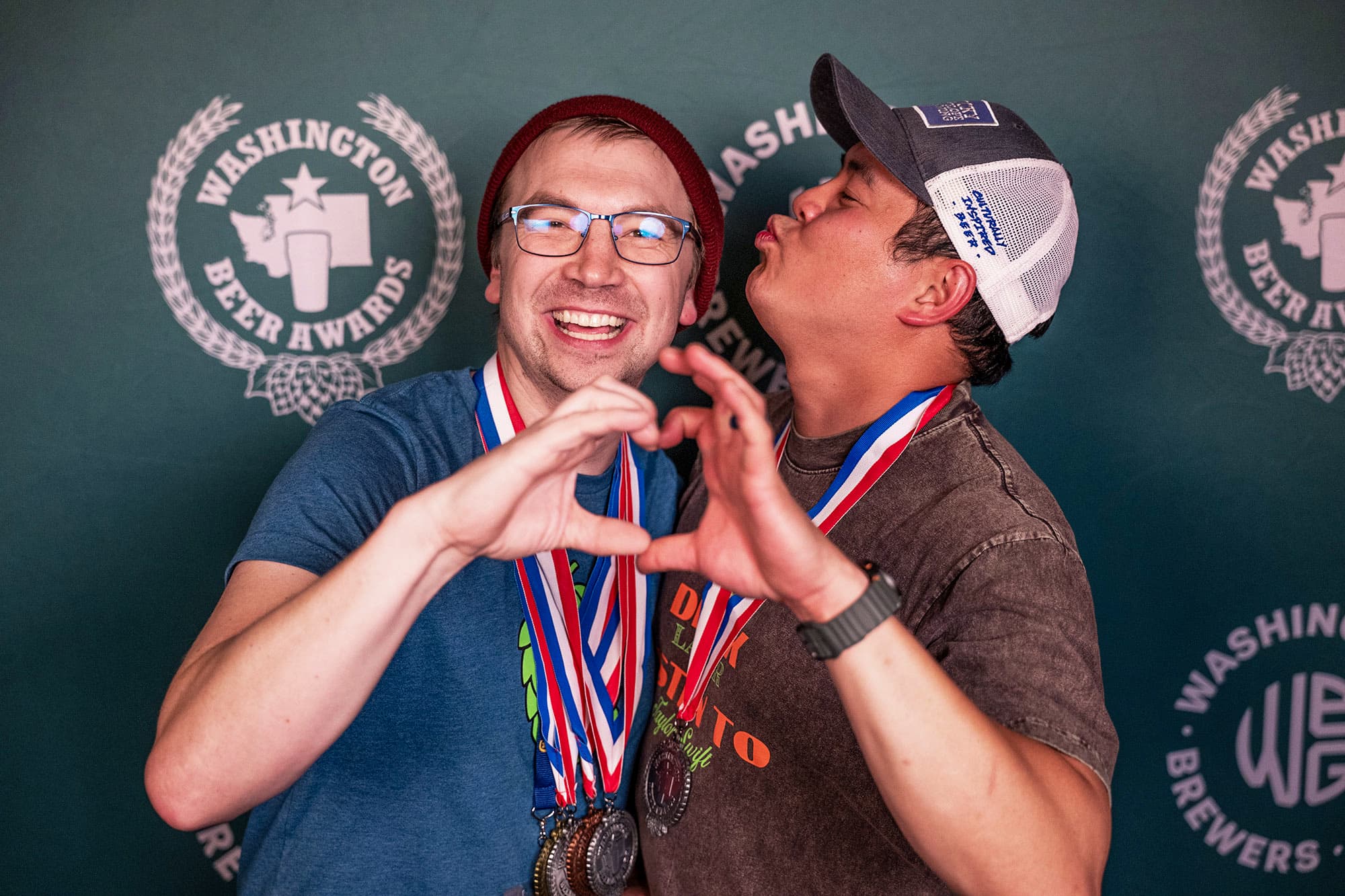 Attendees smiling in front of Washington Beer Awards backdrop at the Craft Beer Summit 2024