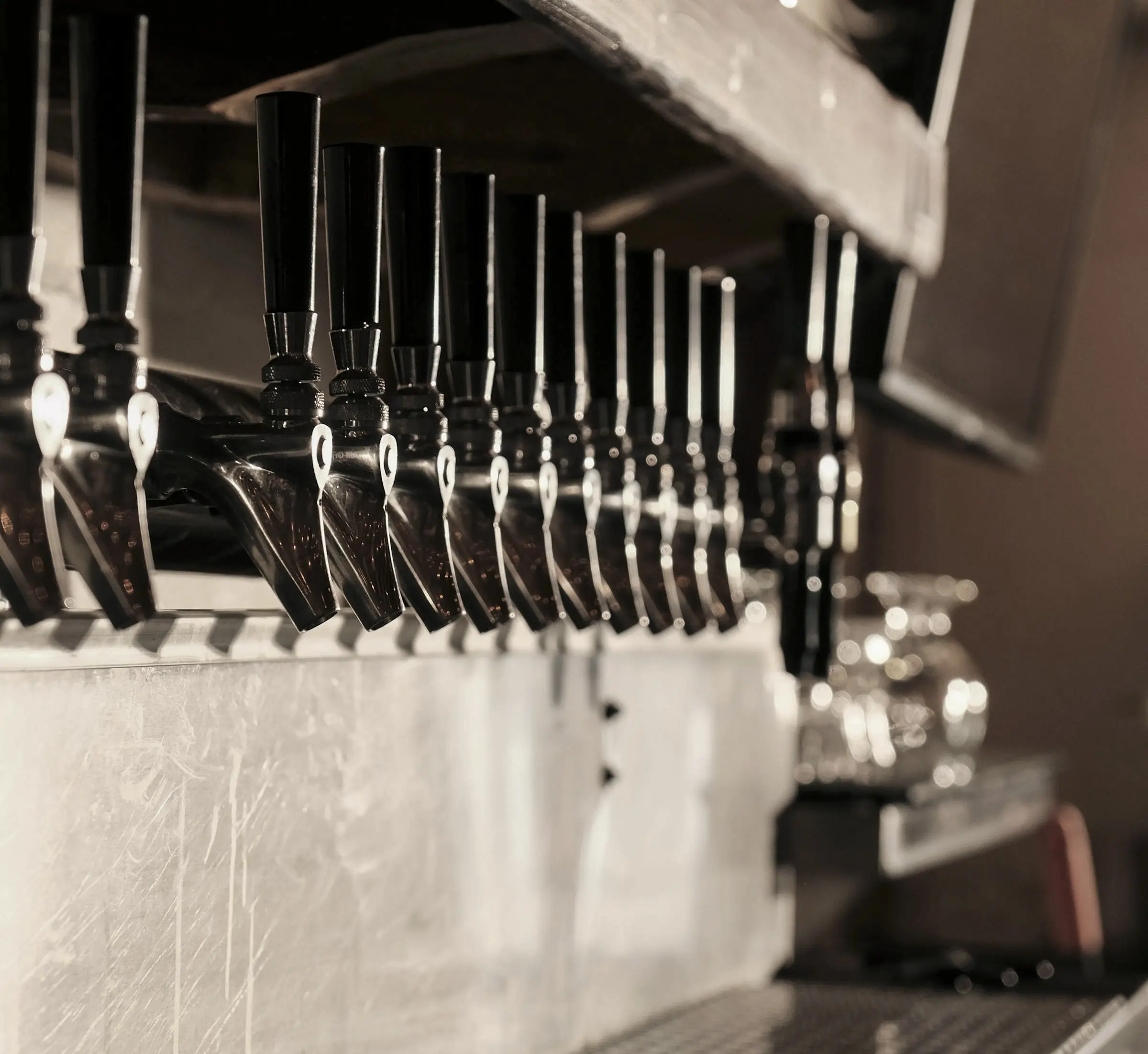 A row of industrial bar taps in a modern bar setting