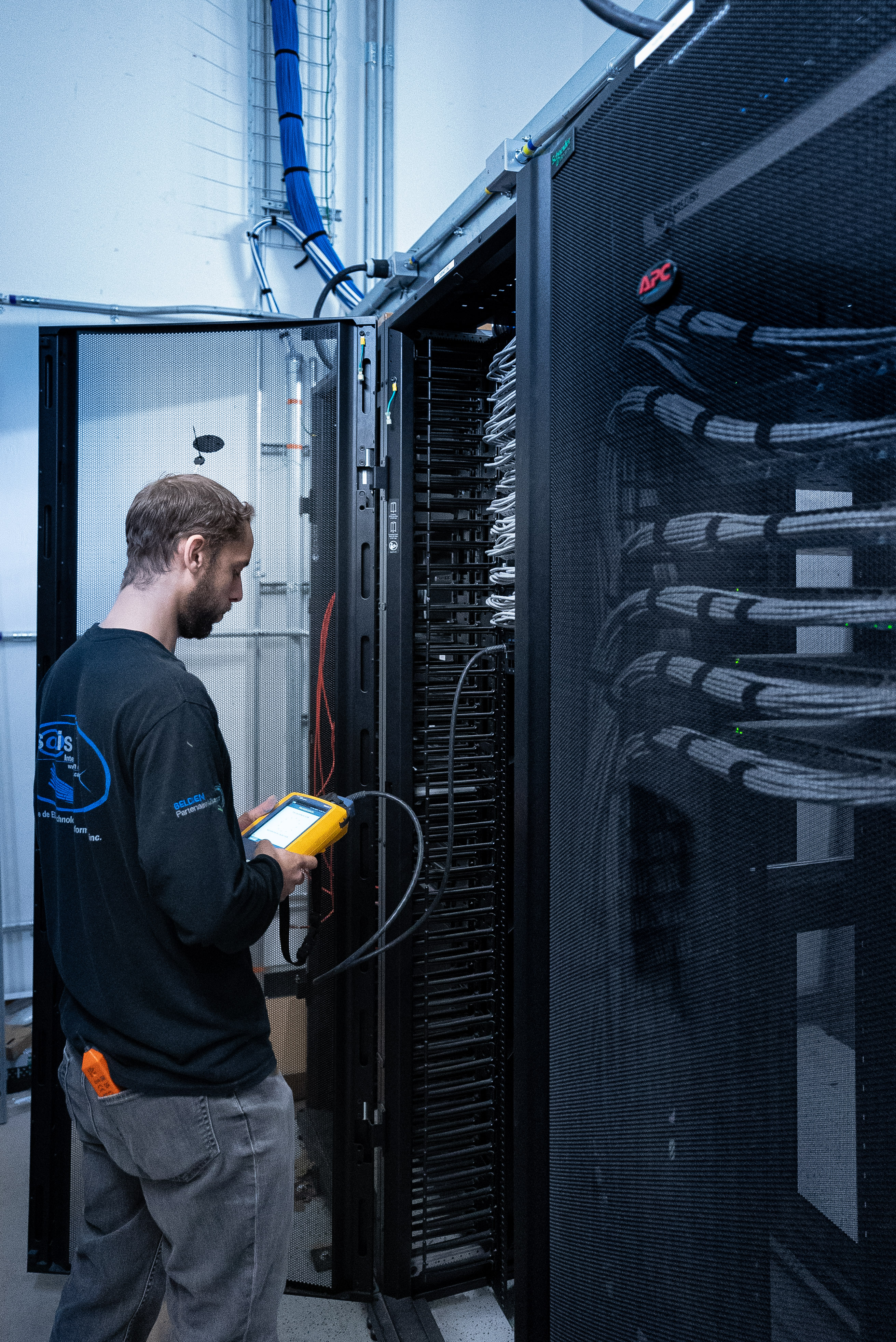 Technicien SAIS certifiant une infrastructure de câblage réseau dans une salle télécom