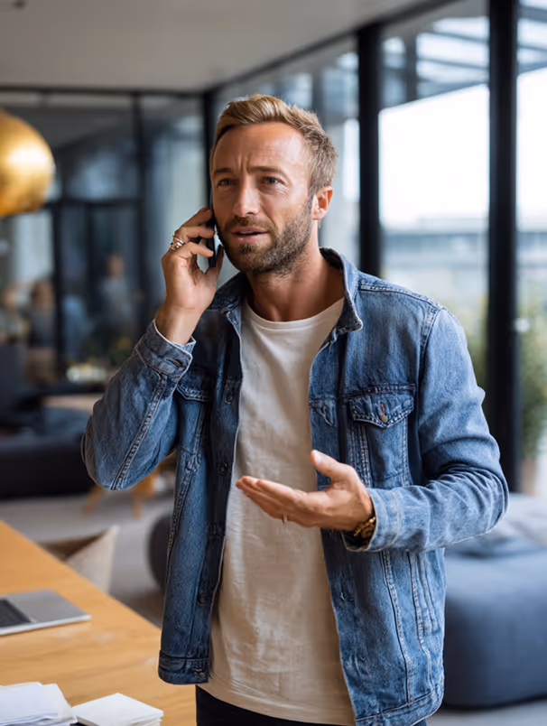 Homme parlant au téléphone avec une expression préoccupée dans un bureau moderne.