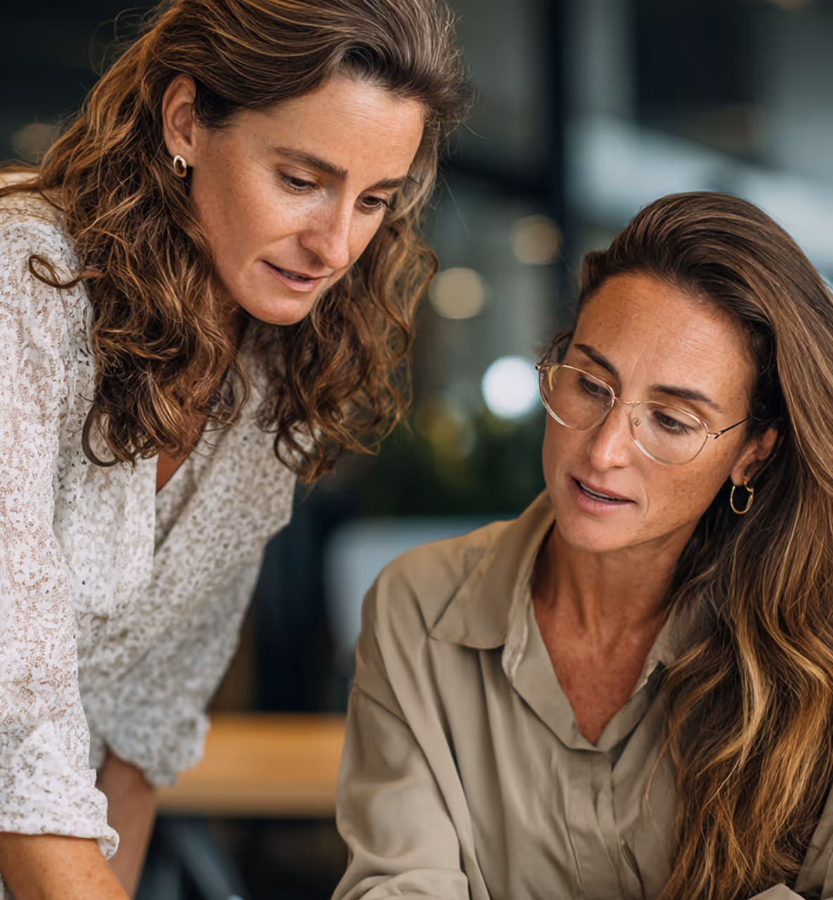 Deux femmes discutant et travaillant ensemble dans un bureau moderne.