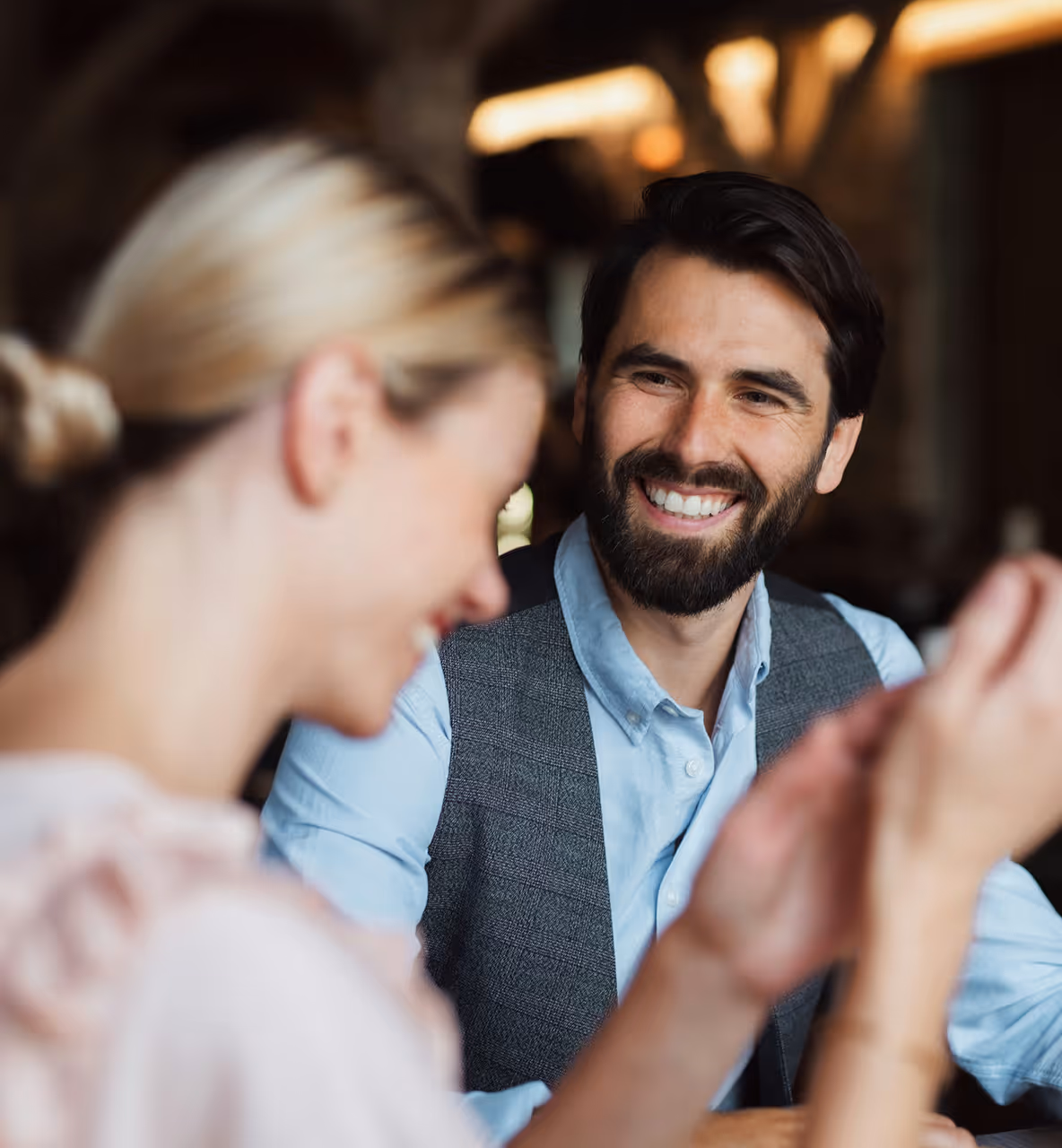 Un homme souriant avec une barbe regarde une femme blonde qui rit.