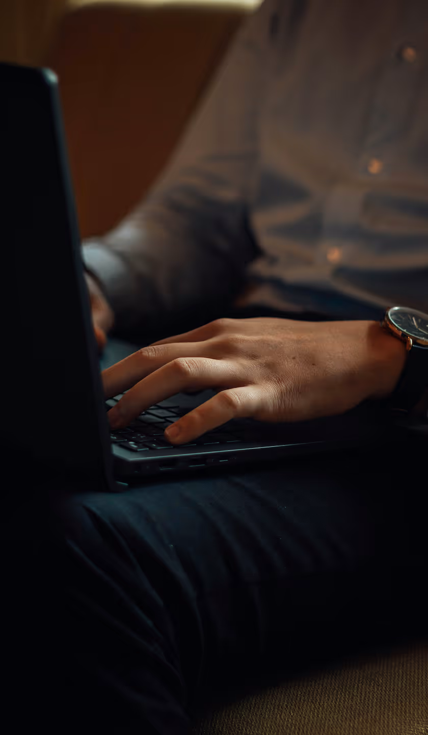 Main d'une personne tapant sur un clavier d'ordinateur portable en tenue décontractée avec une montre au poignet.
