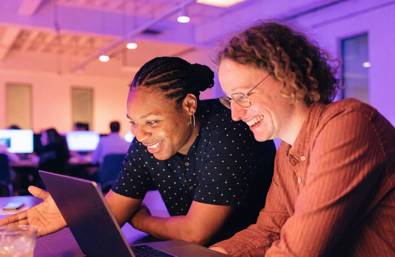 Manager mentoring a colleague on AI tools at a laptop