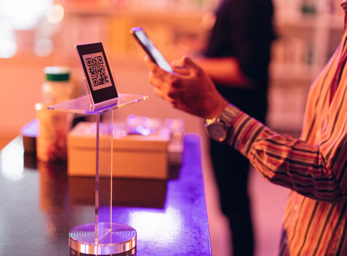 Customer scanning an InvenBoost QR code at a retail counter
