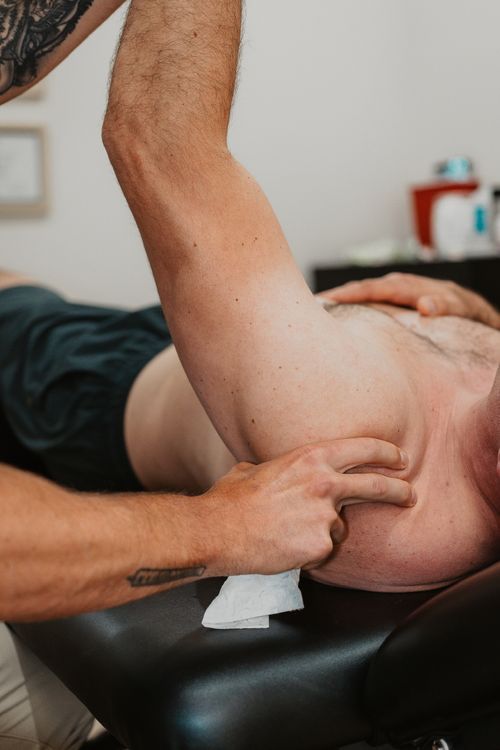 Close-up of a person receiving a deep tissue massage on the upper back and shoulder.