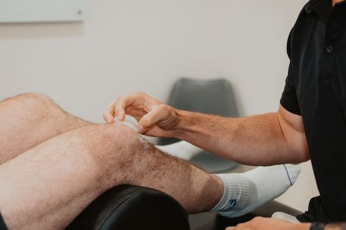 Therapist applying a suction cup to a man's hairy knee during a treatment session.