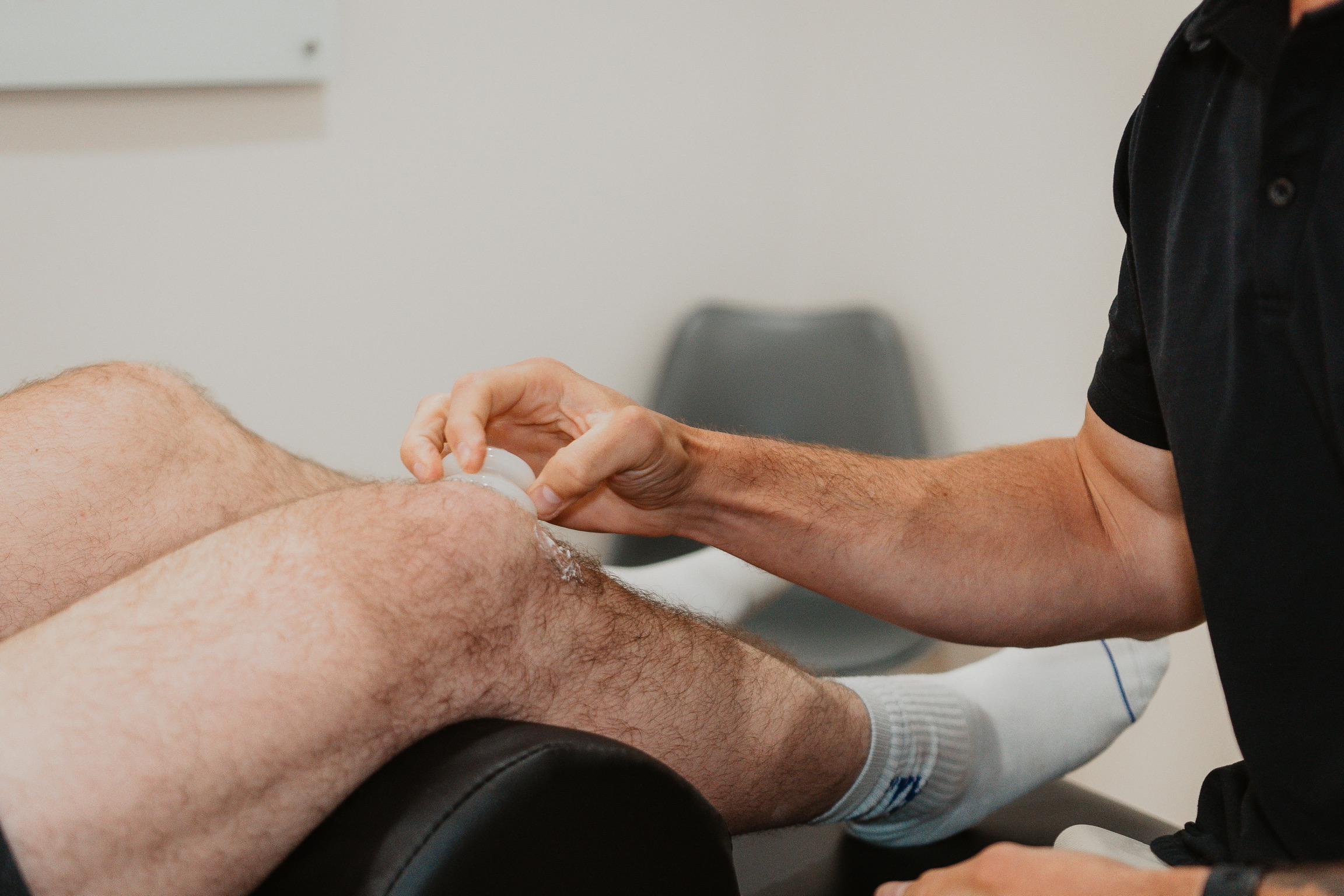 Therapist applying a suction cup to a man's hairy knee during a treatment session.
