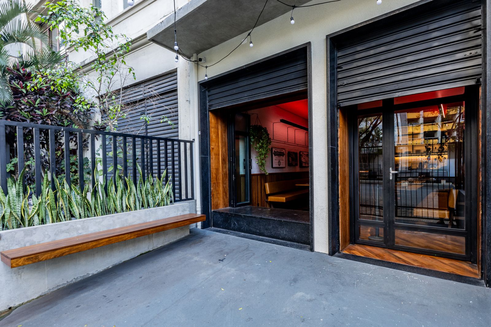 Fachada do Café Capô com portas de vidro e jardim