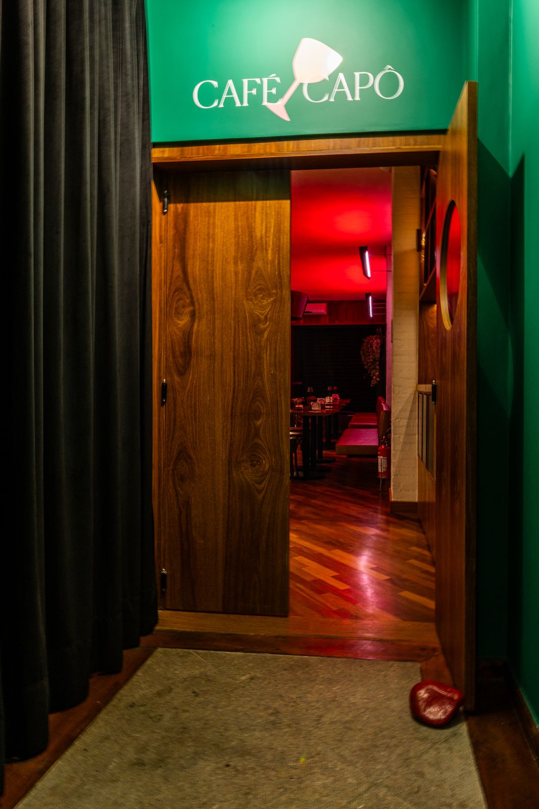 Entrada do Café Capô com a porta aberta para o salão iluminado