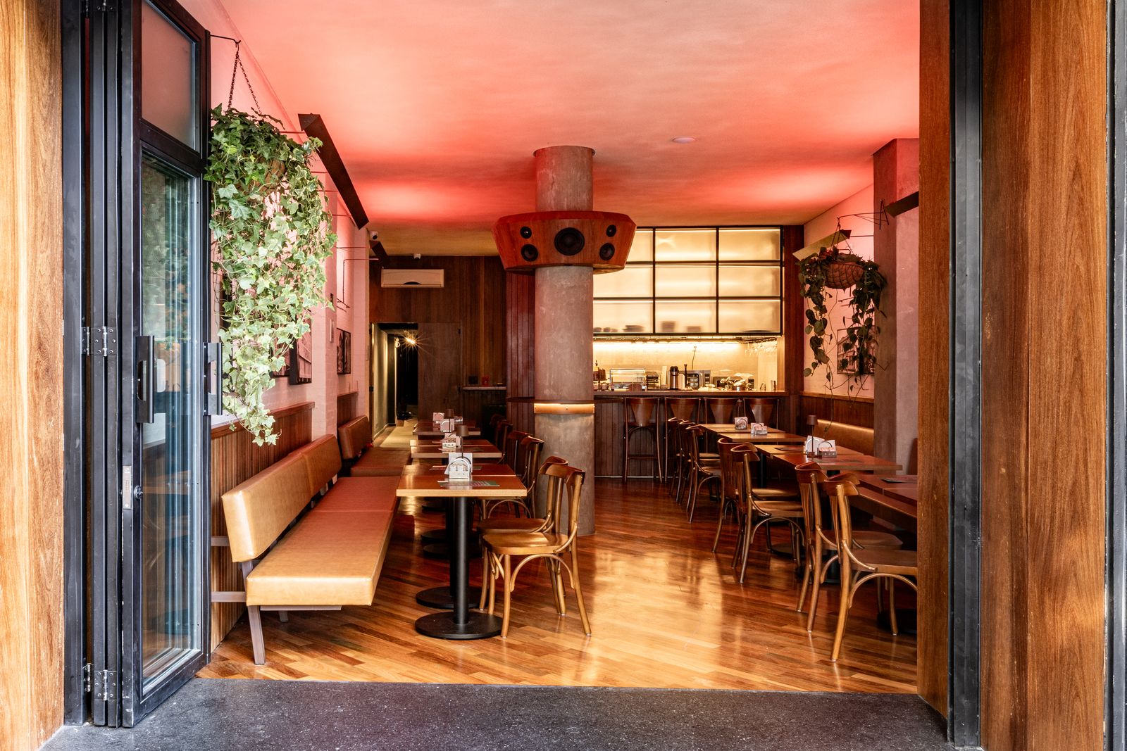 Salão do Café Capô visto da entrada, sob luz rosada