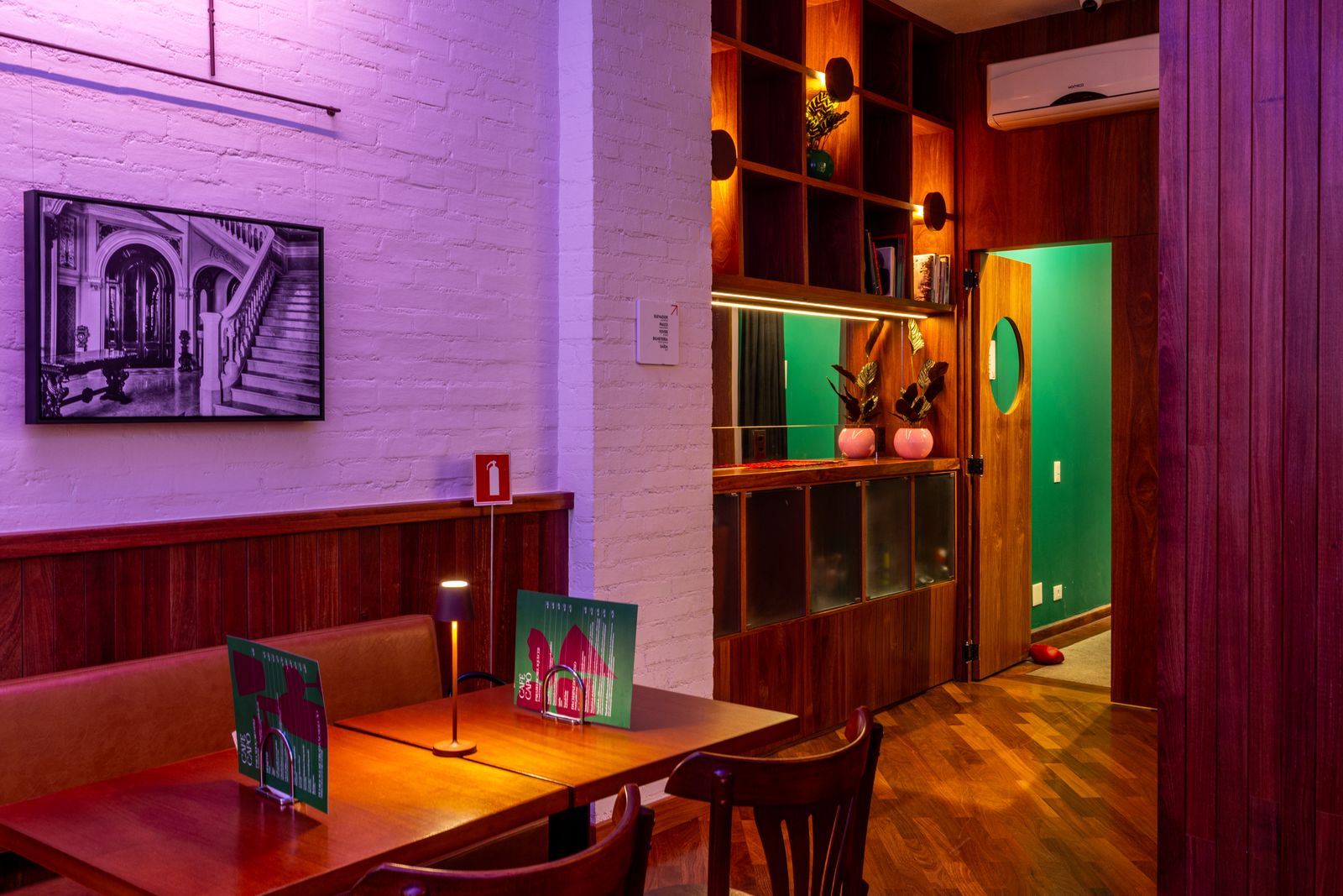 Canto do salão com porta verde e luminárias de mesa