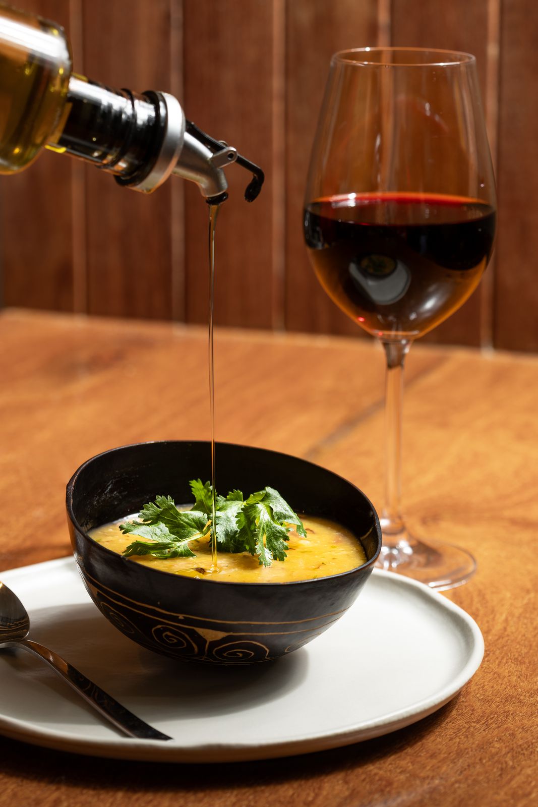 Sopa servida com fio de azeite e taça de vinho tinto