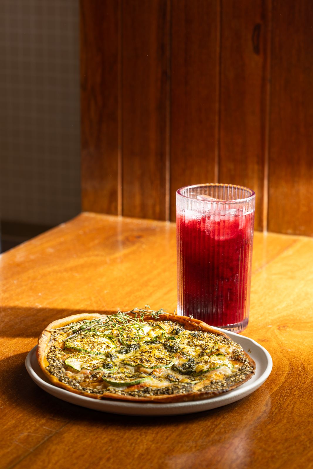 Pizzetta e suco vermelho sobre mesa de madeira